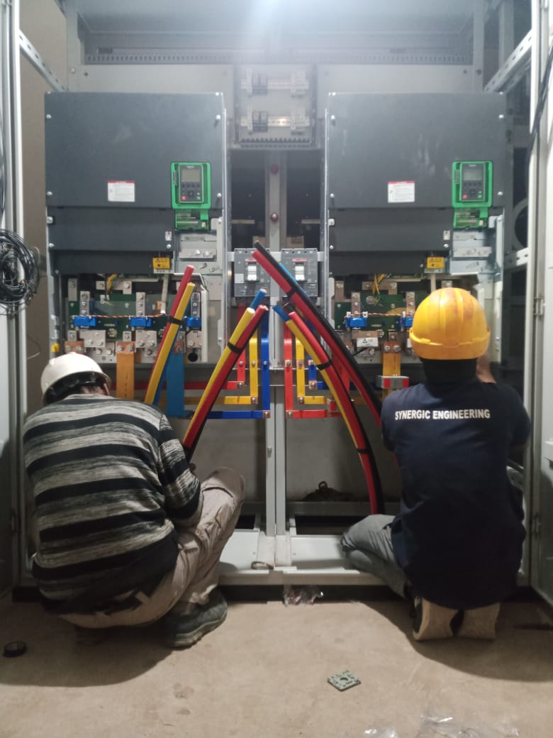 Synergic Engineering technicians working inside an electrical panel
